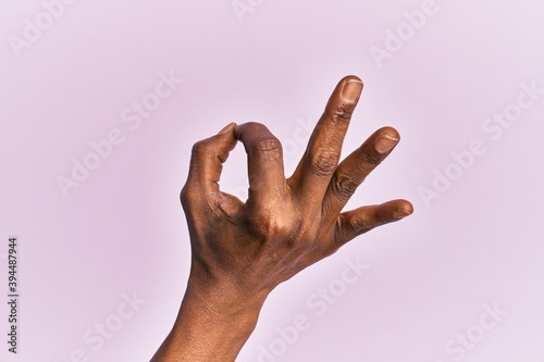Arm and hand of black middle age woman over pink isolated background gesturing approval expression doing okay symbol with fingers