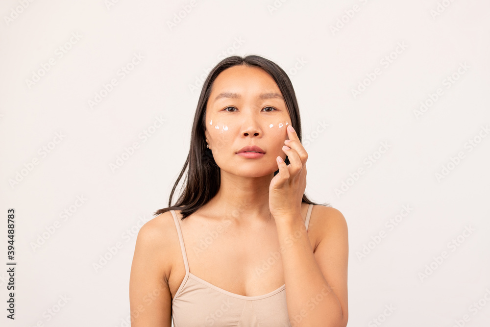 Korean or Chinese girl with dark long hair having undereye mask in isolation Korean or Chinese girl with dark long hair having undereye mask in isolation