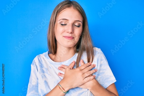 Young blonde girl wearing casual clothes smiling with hands on chest, eyes closed with grateful gesture on face. health concept.