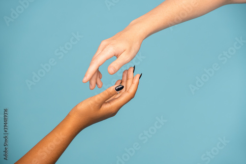 Hands of girls of Caucasian and African ethnicities stretching to each other