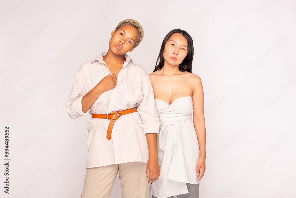 Young Asian woman with long dark hair standing by her African female companion Young Asian woman with long dark hair standing by her African female companion