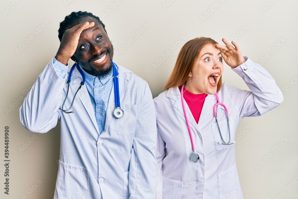 Young interracial couple wearing doctor uniform and stethoscope very happy  and smiling looking far away with hand over head. searching concept. Stock  Photo | Adobe Stock