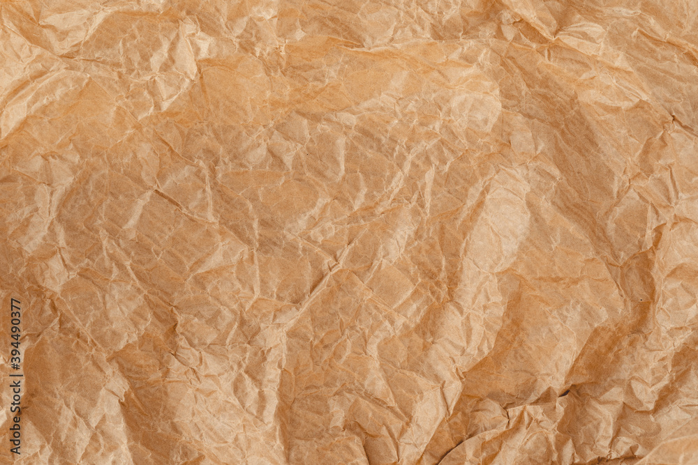 Fototapeta premium Crinkled wrap sheet, recycle grunge texture sample. Closeup of parchment canvas. Wrapping paper material. Kraft paper texture. Brown crumpled surface.