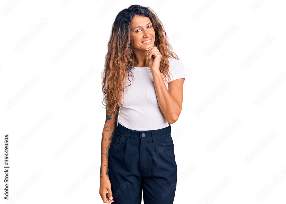 Young hispanic woman with tattoo wearing casual white tshirt looking confident at the camera with smile with crossed arms and hand raised on chin. thinking positive. Young hispanic woman with tattoo wearing casual white tshirt looking confident at the camera with smile with crossed arms and hand raised on chin. thinking positive.