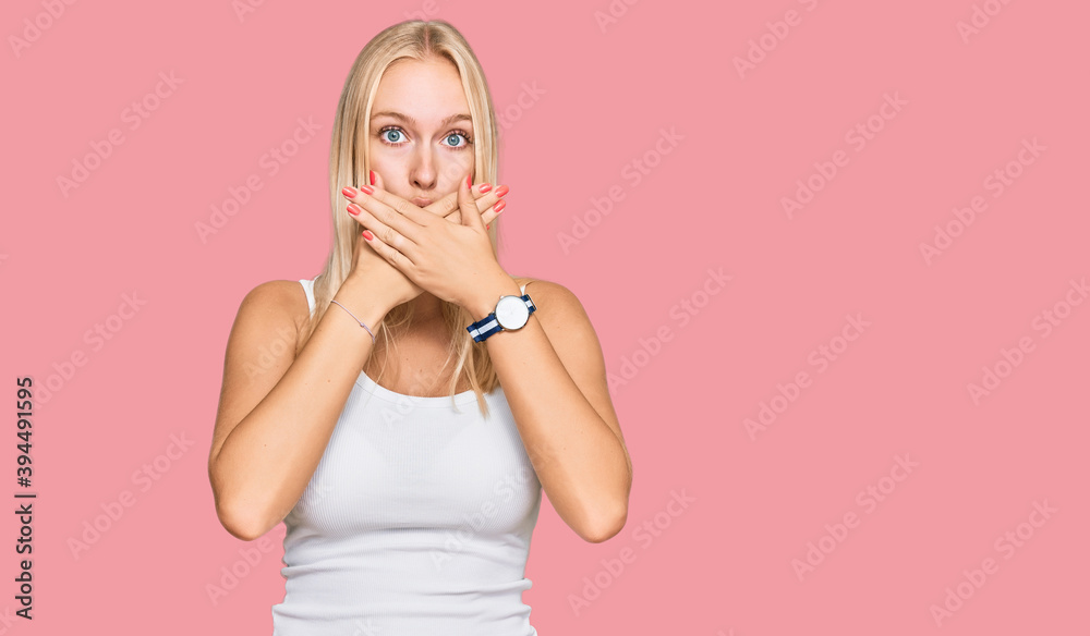 Young blonde girl wearing casual style with sleeveless shirt shocked covering mouth with hands for mistake. secret concept. Young blonde girl wearing casual style with sleeveless shirt shocked covering mouth with hands for mistake. secret concept.