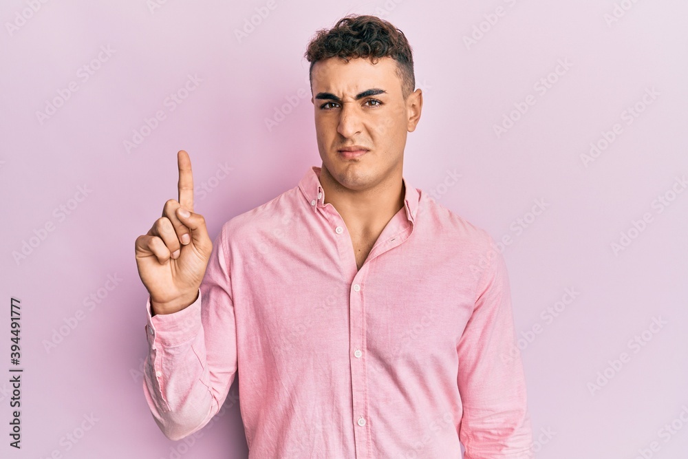Handsome young man pointing up with fingers looking at the camera blowing a kiss being lovely and sexy. love expression. Handsome young man pointing up with fingers looking at the camera blowing a kiss being lovely and sexy. love expression.