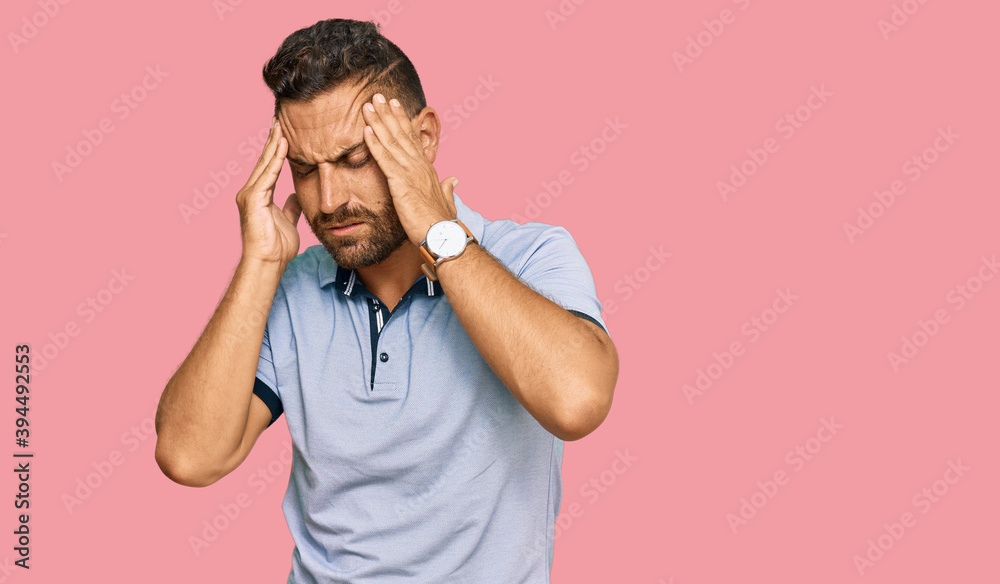 Handsome man with beard wearing casual clothes with hand on head, headache because stress. suffering migraine. Handsome man with beard wearing casual clothes with hand on head, headache because stress. suffering migraine.