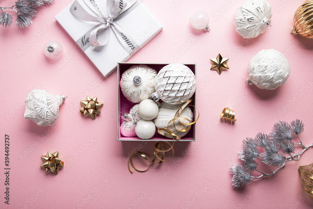 Fototapeta premium Merry Christmas and Happy Holidays greeting card, frame, banner. New Year. Noel. Christmas white silver ornaments and gift box on pink background top view. Winter xmas holiday theme. Flat lay 