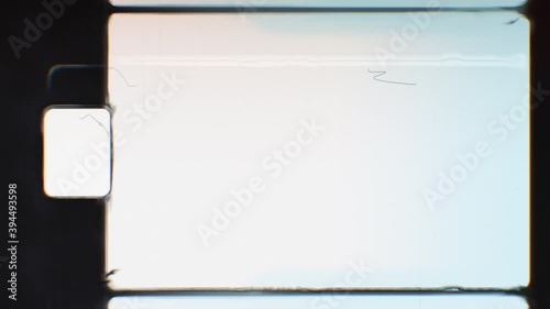Super 8 film frame dynamic texture. Black vignette with sprocket hole or perf on side. Dust, scratchers, hair, noise and grain effect. Realistic film burn background. Retro, vintage style 4K animation