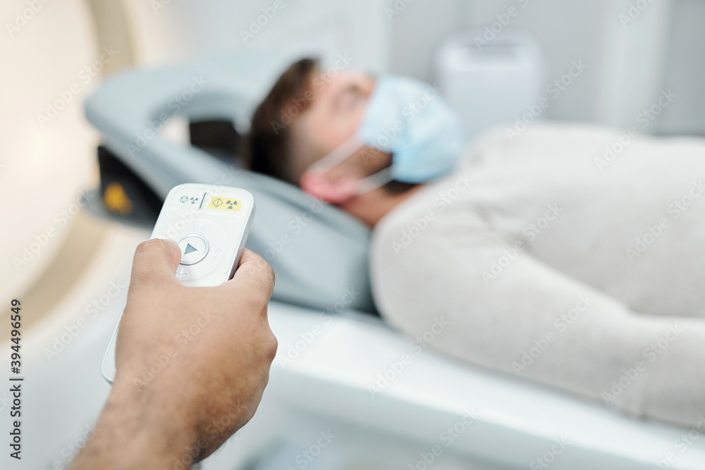 Hand of male touching button on control panel while standing in front of patient Hand of male touching button on control panel while standing in front of patient