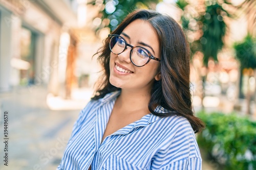 Young hispanic businesswoman smiling happy walking at the city