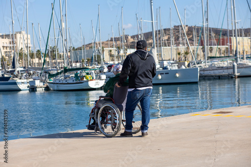 a man walks with an old man in a wheelchair