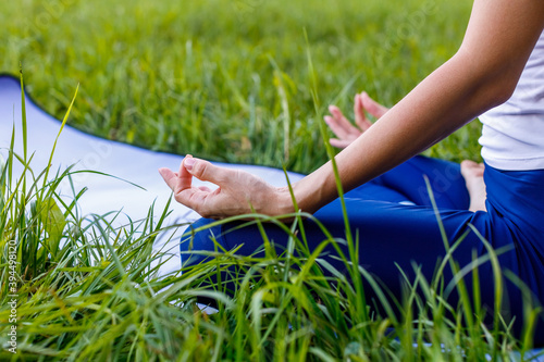 Healthy girl doing yoga in nature in the Park in the summer sitting in the Lotus position. Close up