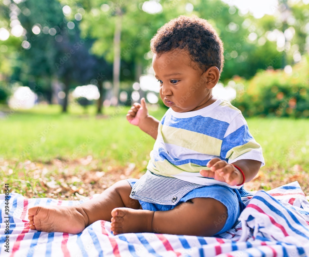Adorable african american toddler sitting on the grass at the park. Adorable african american toddler sitting on the grass at the park.