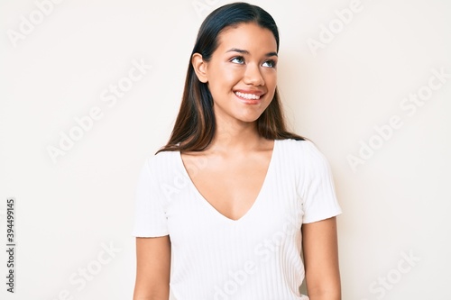 Young beautiful latin girl wearing casual white tshirt looking to side, relax profile pose with natural face and confident smile. © Krakenimages.com
