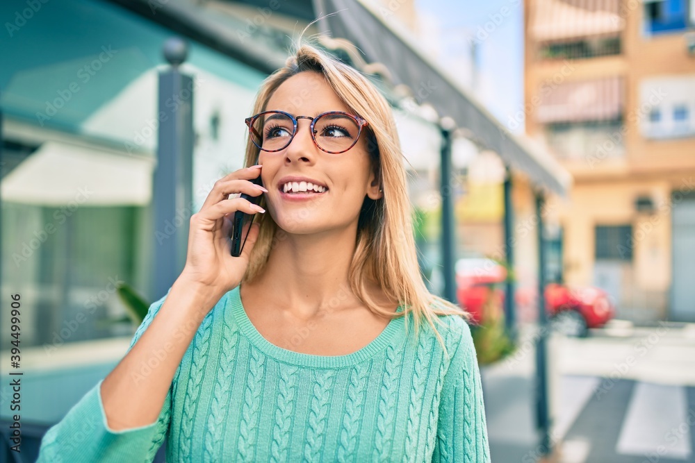 Fototapeta premium Young blonde woman smiling happy talking on the smartphone at the city.
