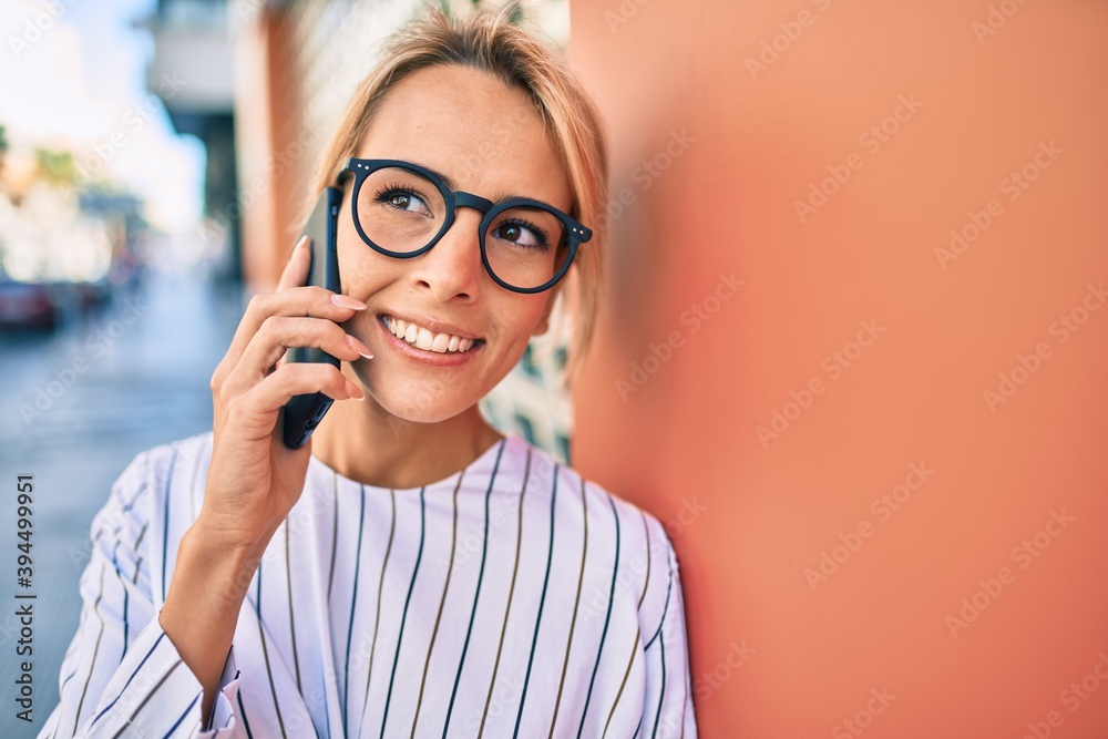 Young blonde businesswoman smiling happy using smartphone at the city. Young blonde businesswoman smiling happy using smartphone at the city.