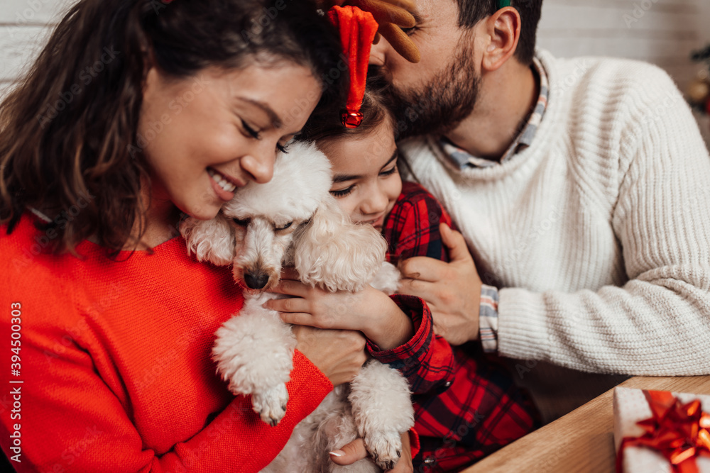 Young father, mother and daughter celebrating New year at their home. Festive family indoors concept. Young father, mother and daughter celebrating New year at their home. Festive family indoors concept.