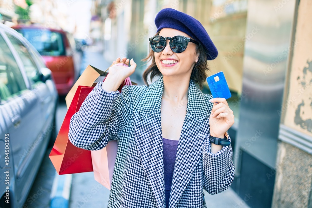 Young beautiful girl smiling happy with french style holding shopping bags and credit card at street of city Young beautiful girl smiling happy with french style holding shopping bags and credit card at street of city