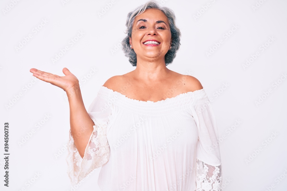 Senior hispanic grey- haired woman wearing casual clothes smiling cheerful presenting and pointing with palm of hand looking at the camera. Senior hispanic grey- haired woman wearing casual clothes smiling cheerful presenting and pointing with palm of hand looking at the camera.