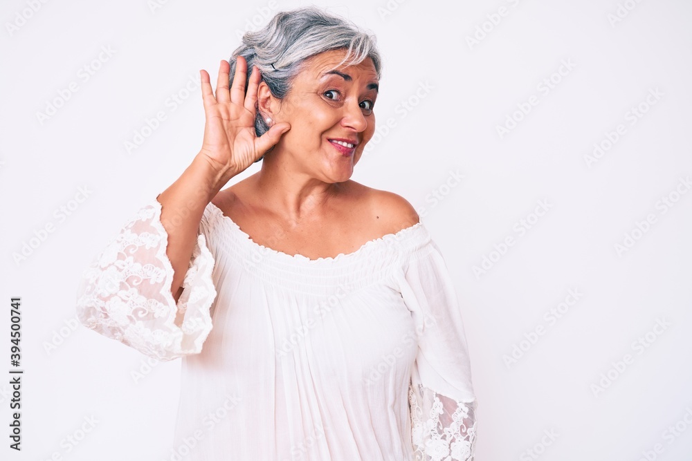 Senior hispanic grey- haired woman wearing casual clothes smiling with hand over ear listening an hearing to rumor or gossip. deafness concept. Senior hispanic grey- haired woman wearing casual clothes smiling with hand over ear listening an hearing to rumor or gossip. deafness concept.