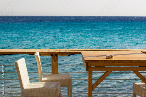 patio of rustic furniture chairs and table without people here on waterfront district with Mediterranean sea summer nature scenic background