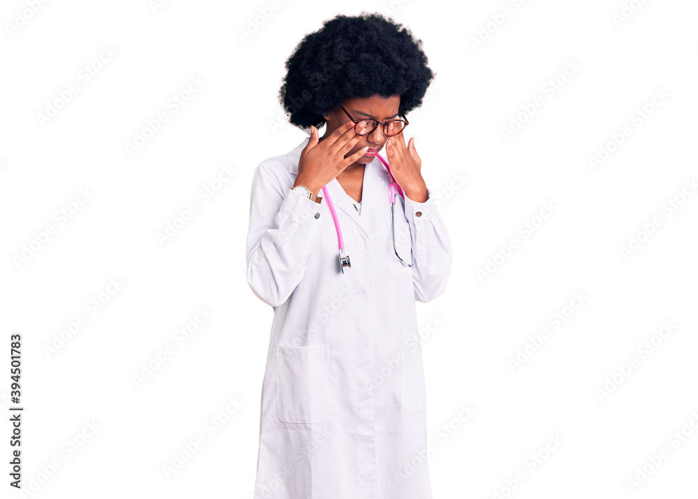 Young african american woman wearing doctor coat and stethoscope rubbing eyes for fatigue and headache, sleepy and tired expression. vision problem Young african american woman wearing doctor coat and stethoscope rubbing eyes for fatigue and headache, sleepy and tired expression. vision problem
