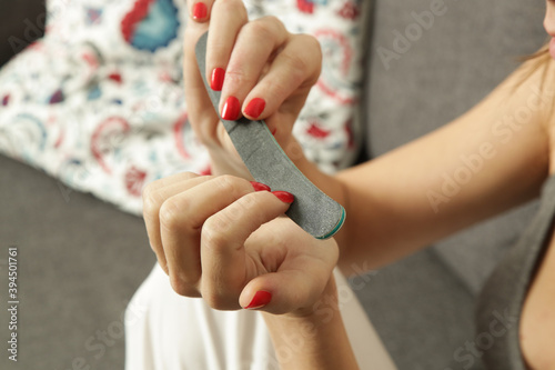 Young woman using nail file at home. Home manicure and nail care concept. 