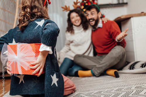 Young father, mother and daughter celebrating New year at their home. Festive family indoors concept.