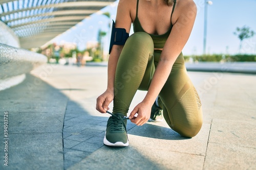 Sportswoman wearing sportswear tying her shoelaces at the city