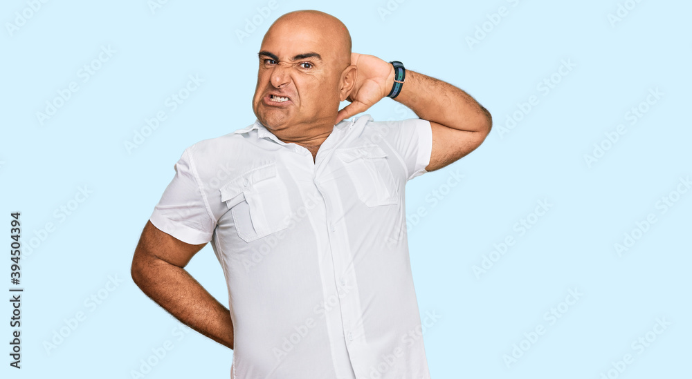 Mature middle east man with mustache wearing casual white shirt suffering of neck ache injury, touching neck with hand, muscular pain Mature middle east man with mustache wearing casual white shirt suffering of neck ache injury, touching neck with hand, muscular pain