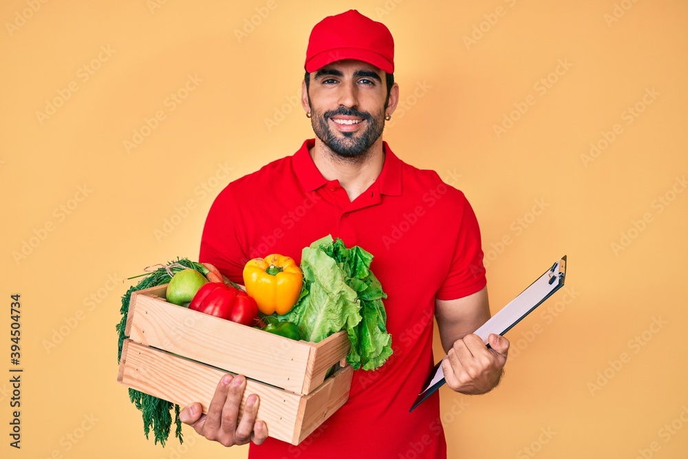 Handsome hispanic man with beard wearing uniform holding delivery food smiling with a happy and cool smile on face. showing teeth. Handsome hispanic man with beard wearing uniform holding delivery food smiling with a happy and cool smile on face. showing teeth.