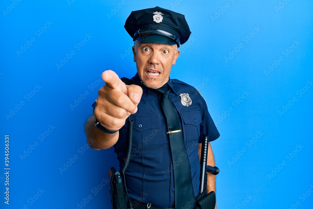 Handsome middle age mature man wearing police uniform pointing displeased and frustrated to the camera, angry and furious with you Handsome middle age mature man wearing police uniform pointing displeased and frustrated to the camera, angry and furious with you