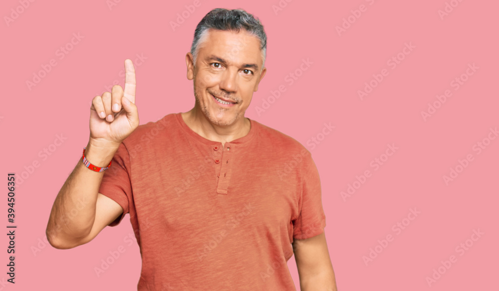 Handsome middle age man wearing casual clothes showing and pointing up with finger number one while smiling confident and happy. Handsome middle age man wearing casual clothes showing and pointing up with finger number one while smiling confident and happy.