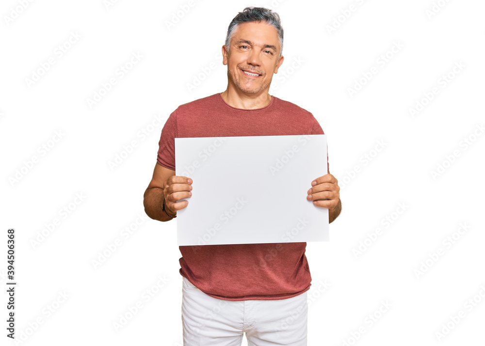 Handsome middle age man holding blank empty banner looking positive and happy standing and smiling with a confident smile showing teeth Handsome middle age man holding blank empty banner looking positive and happy standing and smiling with a confident smile showing teeth