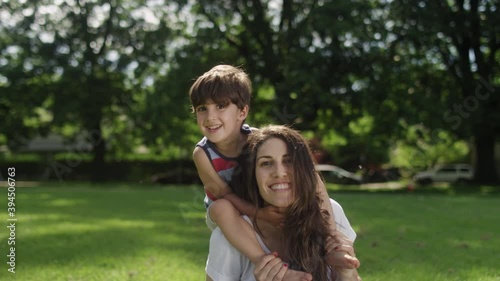 Portrait of a beautiful young mother with her son sitting on her shoulders at the park