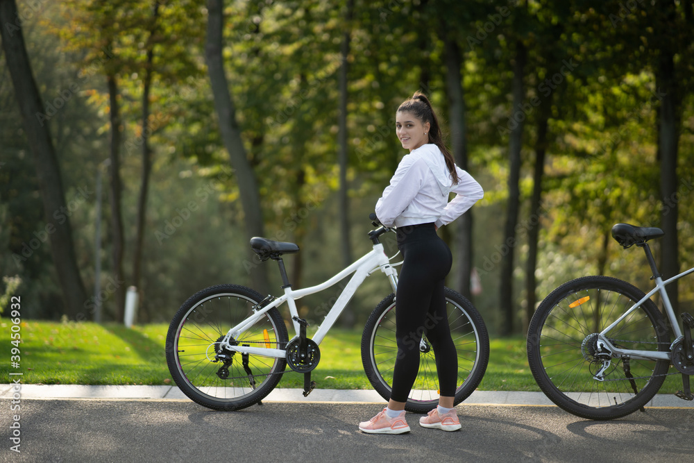 Beautiful girl posing at white bicycle. Walk in nature.