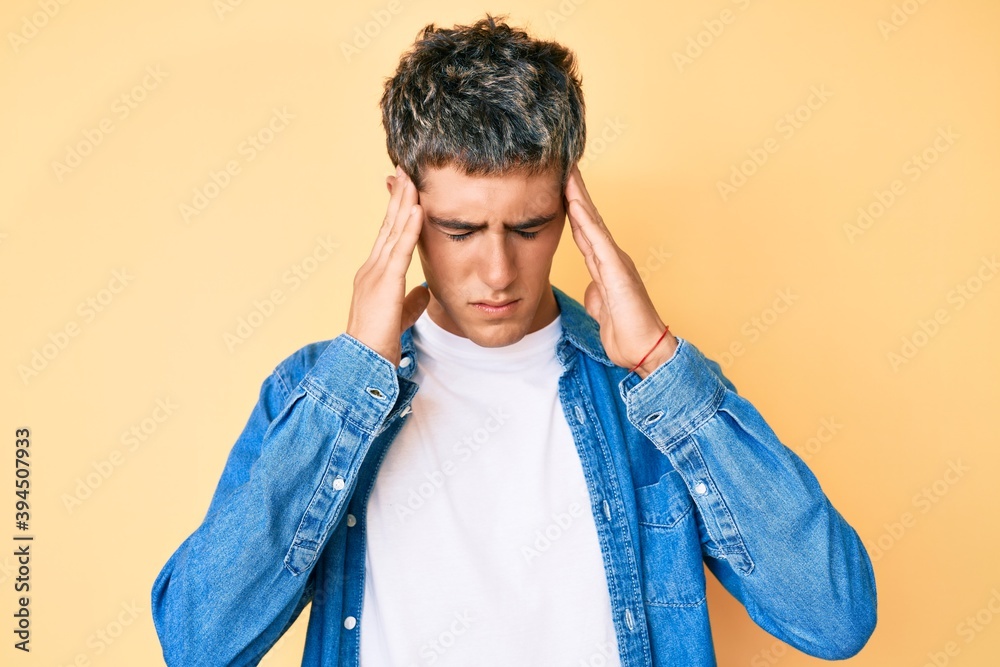Young handsome man wearing casual clothes with hand on head for pain in head because stress. suffering migraine. Young handsome man wearing casual clothes with hand on head for pain in head because stress. suffering migraine.
