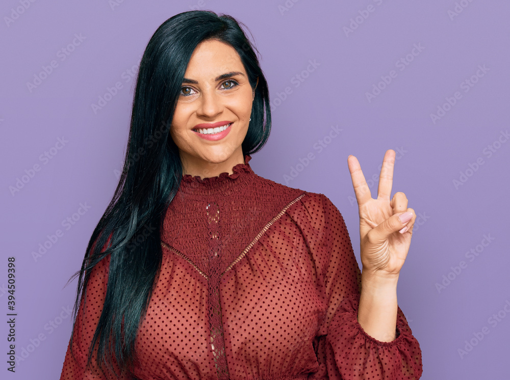 Young caucasian woman wearing casual clothes smiling with happy face winking at the camera doing victory sign. number two. Young caucasian woman wearing casual clothes smiling with happy face winking at the camera doing victory sign. number two.
