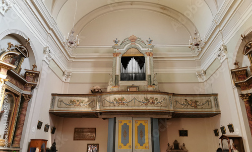 Antico organo a canne con palco in legno dipinto sull’ abside di una chiesa e portone principale photo