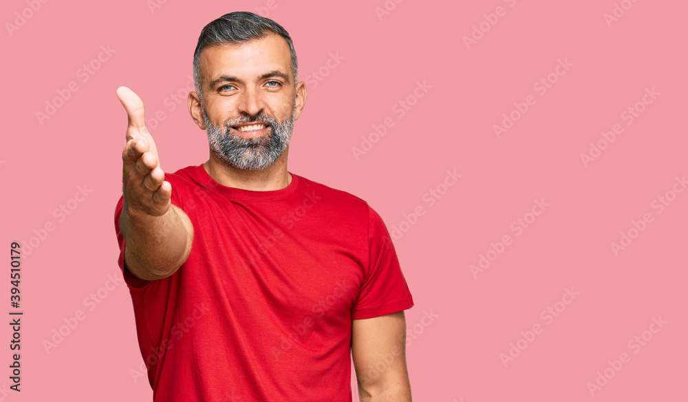 Middle age handsome man wearing casual clothes smiling friendly offering handshake as greeting and welcoming. successful business. Middle age handsome man wearing casual clothes smiling friendly offering handshake as greeting and welcoming. successful business.