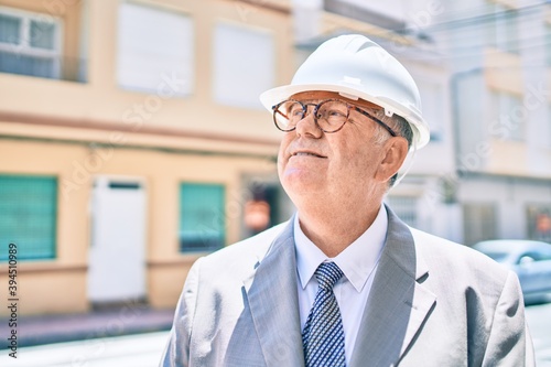 Senior grey-haired architect man smiling happy walking at street of city