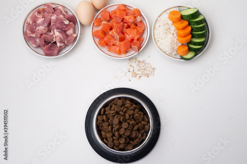 Dry pet dog food in bowl with natural ingredients. Raw meat, fish, vegetables, eggs and salad. concept of correct balanced and healthy nutrition for pet