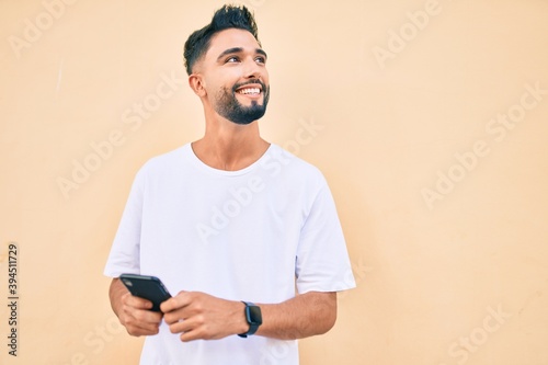 Young arab man smiling happy using smartphone at the city.