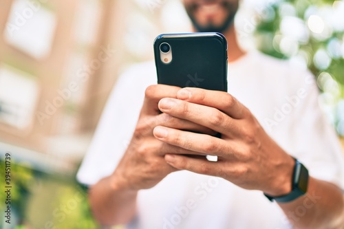 Young arab man smiling happy using smartphone at the city.