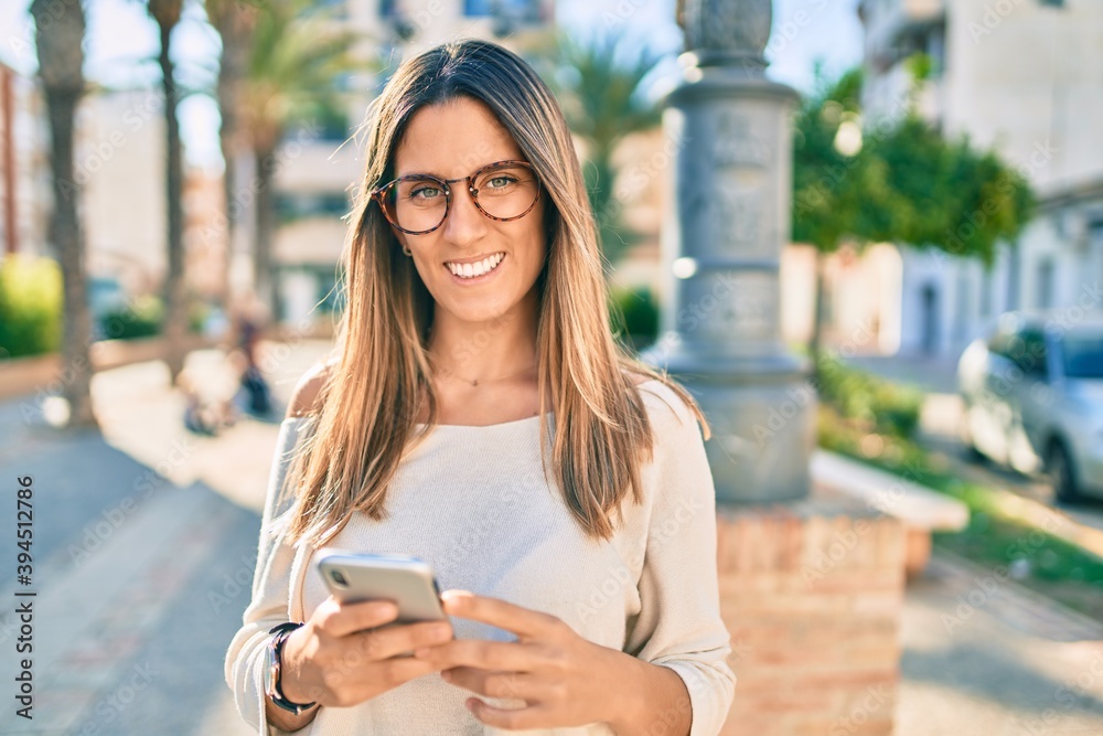 Young caucasian woman smiling happy using smartphone at the city.