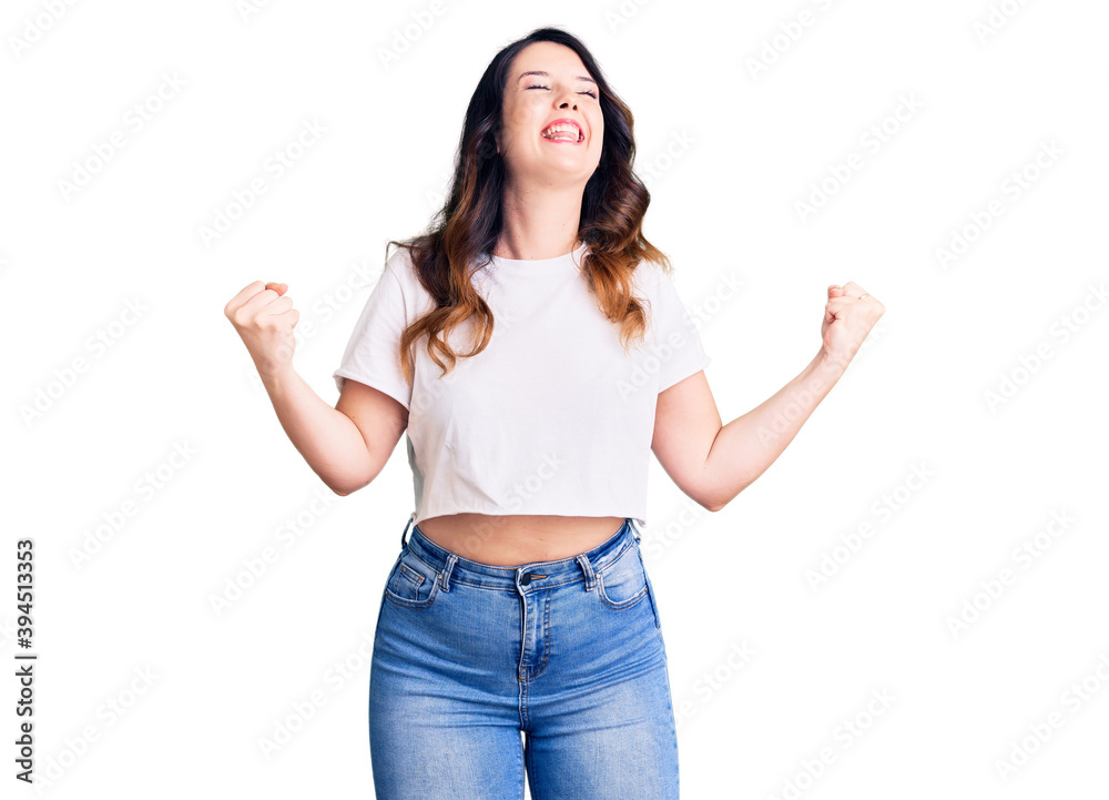 Beautiful young brunette woman wearing casual clothes very happy and excited doing winner gesture with arms raised, smiling and screaming for success. celebration concept. Beautiful young brunette woman wearing casual clothes very happy and excited doing winner gesture with arms raised, smiling and screaming for success. celebration concept.