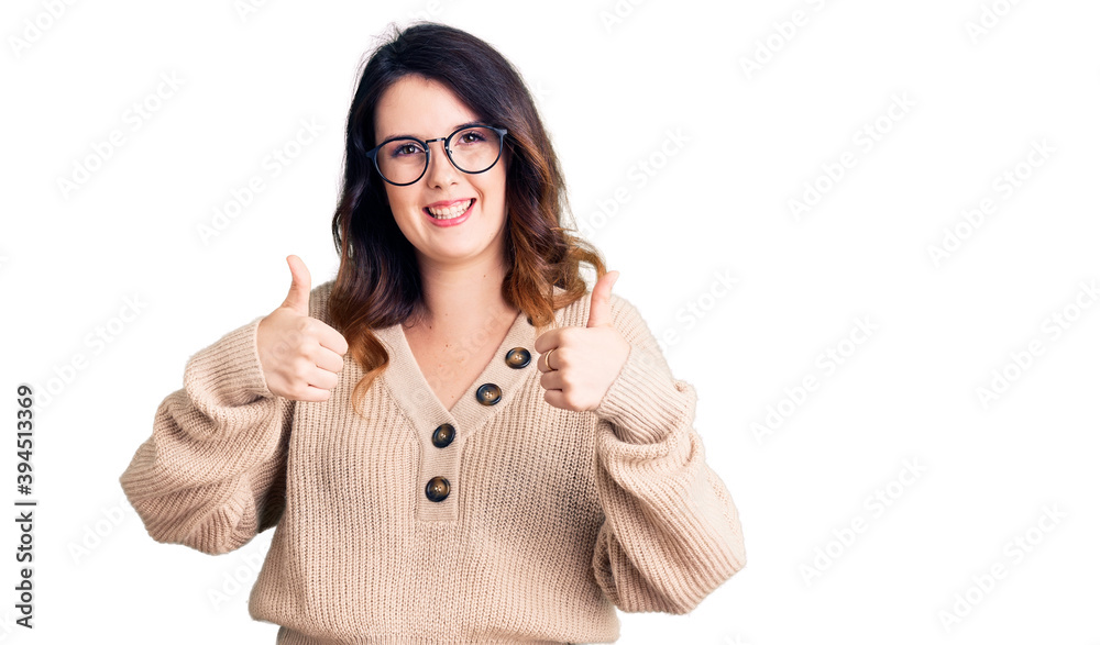 Beautiful young brunette woman wearing casual clothes and glasses success sign doing positive gesture with hand, thumbs up smiling and happy. cheerful expression and winner gesture. Beautiful young brunette woman wearing casual clothes and glasses success sign doing positive gesture with hand, thumbs up smiling and happy. cheerful expression and winner gesture.
