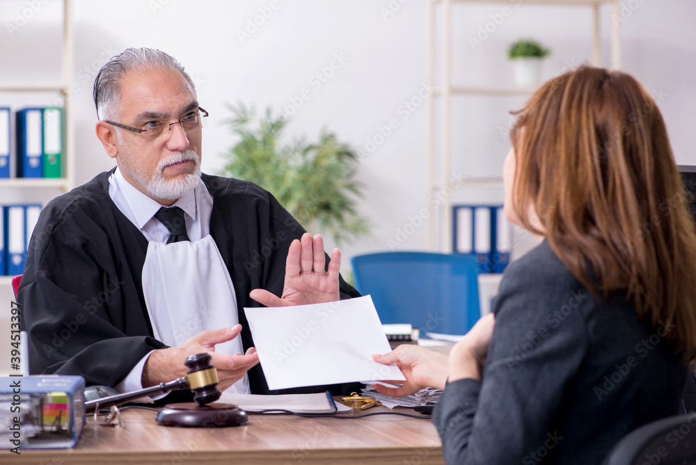 Old male judge and female client in the office Old male judge and female client in the office