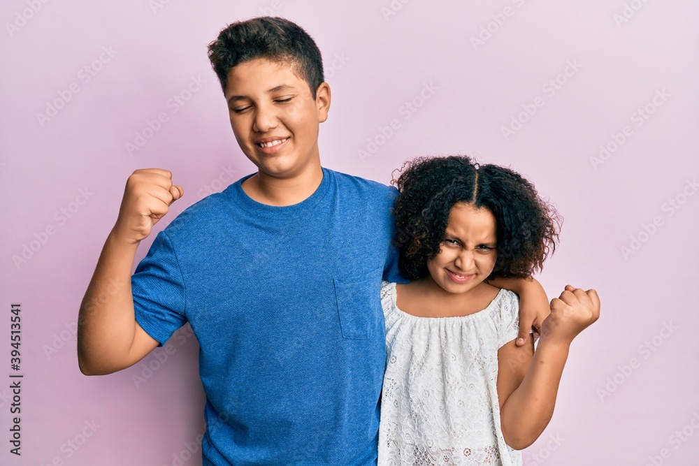 Hispanic teenager brother and little sister wearing casual clothes hugging together skeptic and nervous, frowning upset because of problem. negative person. Hispanic teenager brother and little sister wearing casual clothes hugging together skeptic and nervous, frowning upset because of problem. negative person.